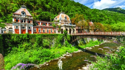 Historic pavilion and iron bridge over a small river.